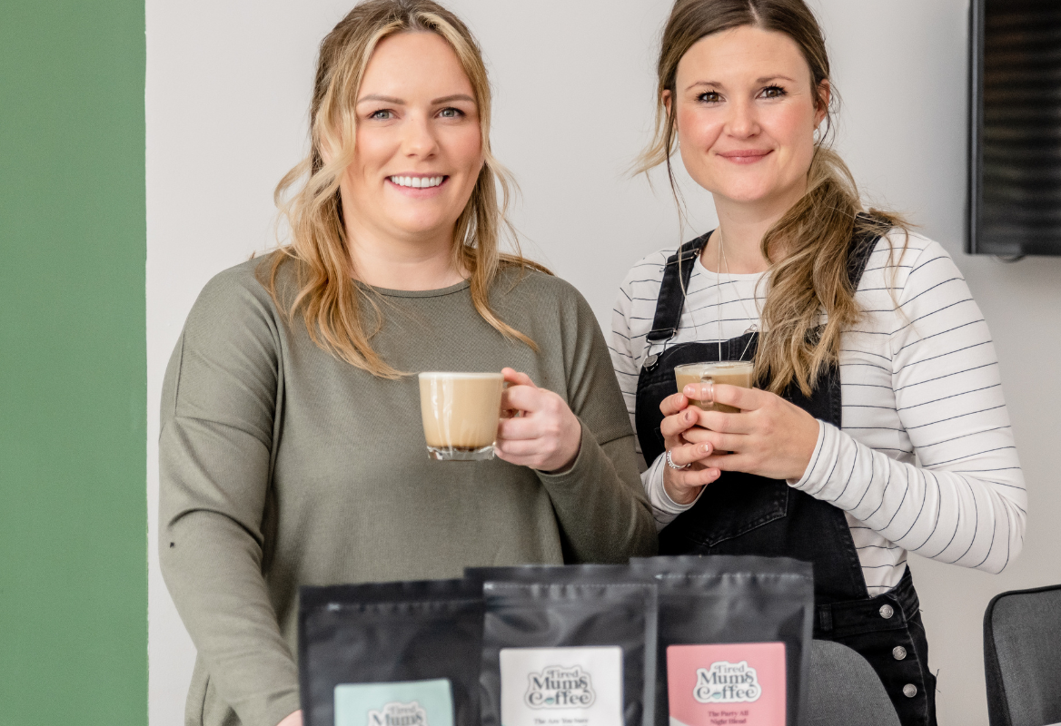 Founders of Tired Mums Coffee looking directly at the camera, with coffee cups in hand.