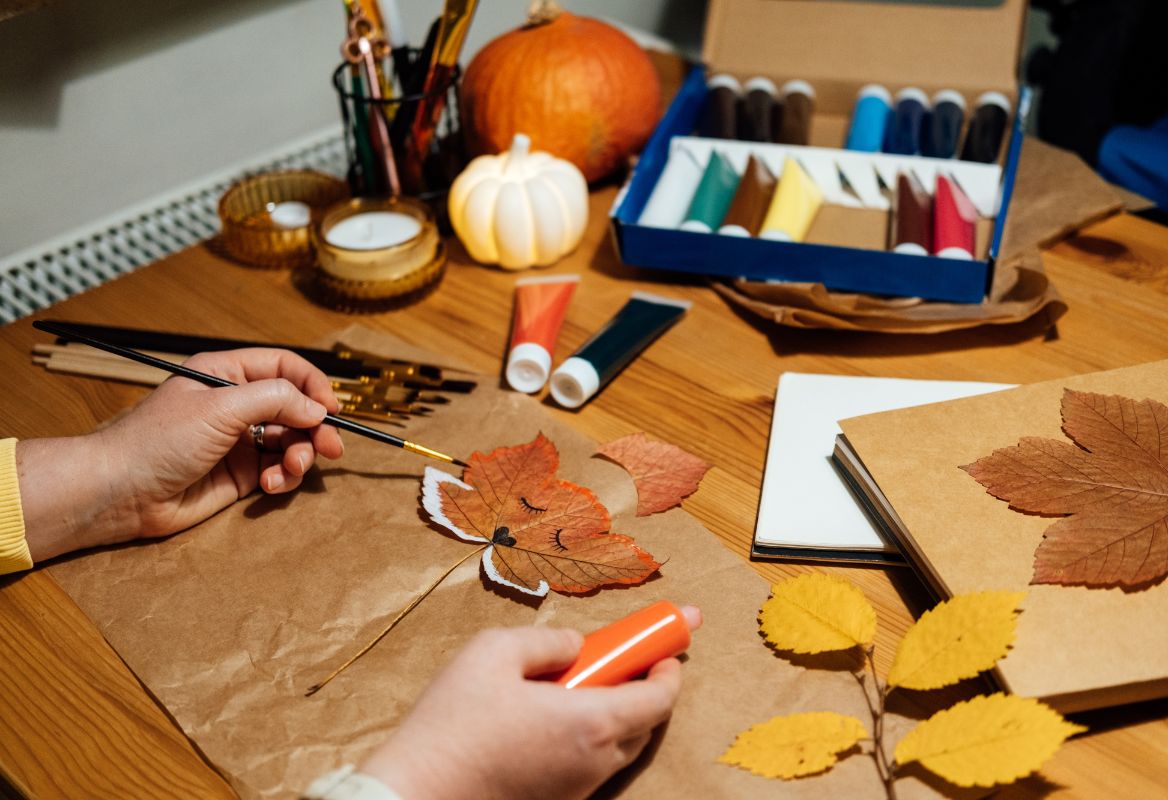 childs hands with small paint brush in hand, making autumn crafts 